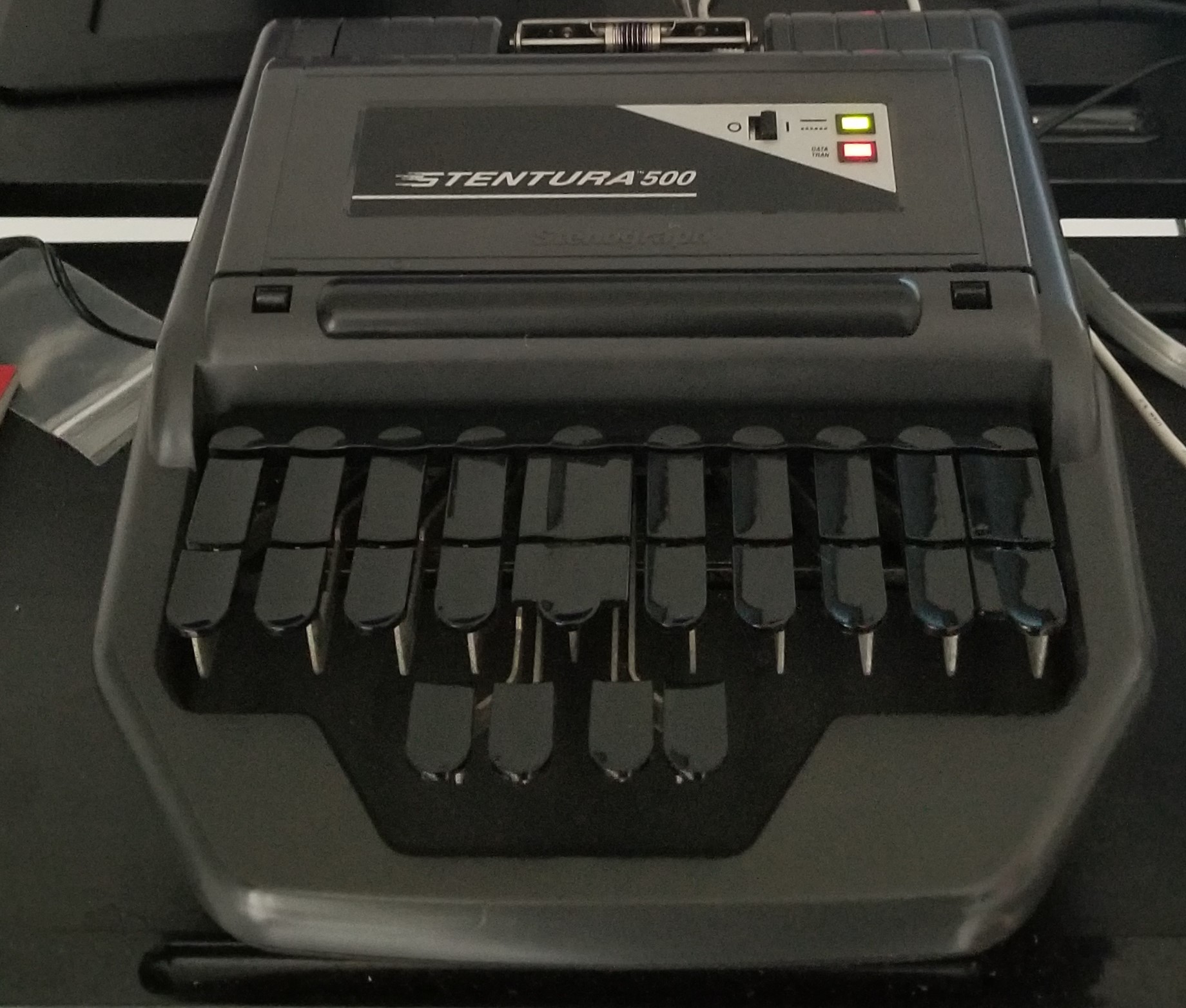 A Stentura 500. This is a fairly old serial port based stenograph. It has the classic keyboard described above in a level configuration, and a paper tape dispenser.